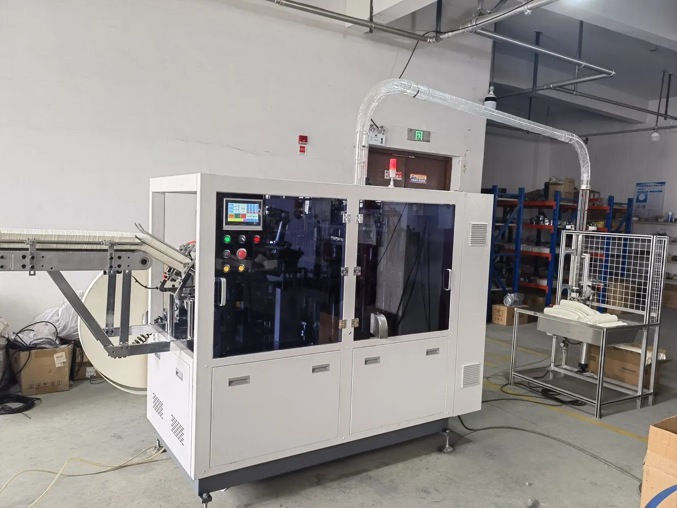 High-speed paper cup machine in a workshop with cup feed and collection systems